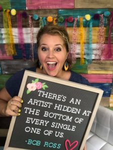 Tamara holding Bob Ross quote on letter board