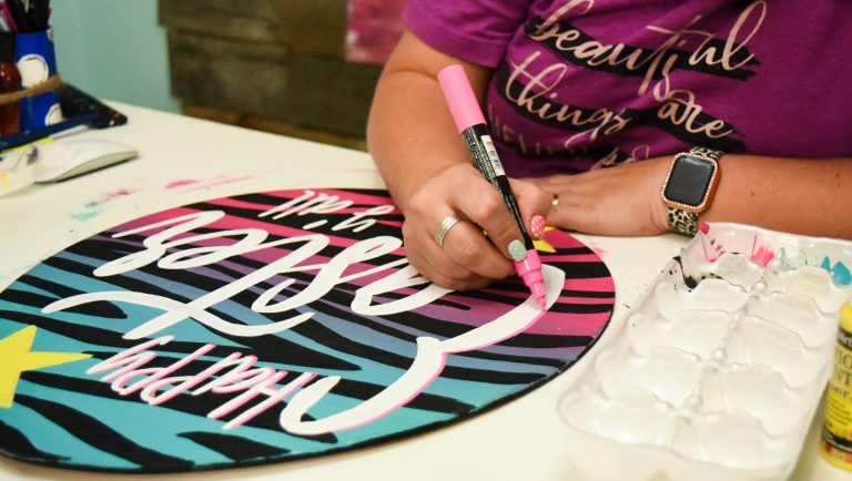 Using a paint pen to add a drop shadow to the lettering on a door hanger