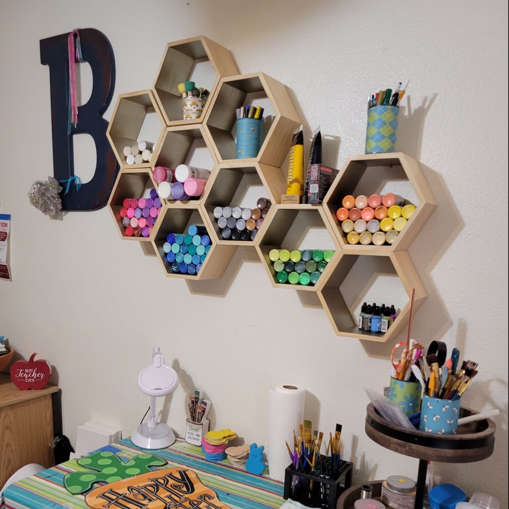 Paint Bottles stored in a wooden honeycomb shape on wall