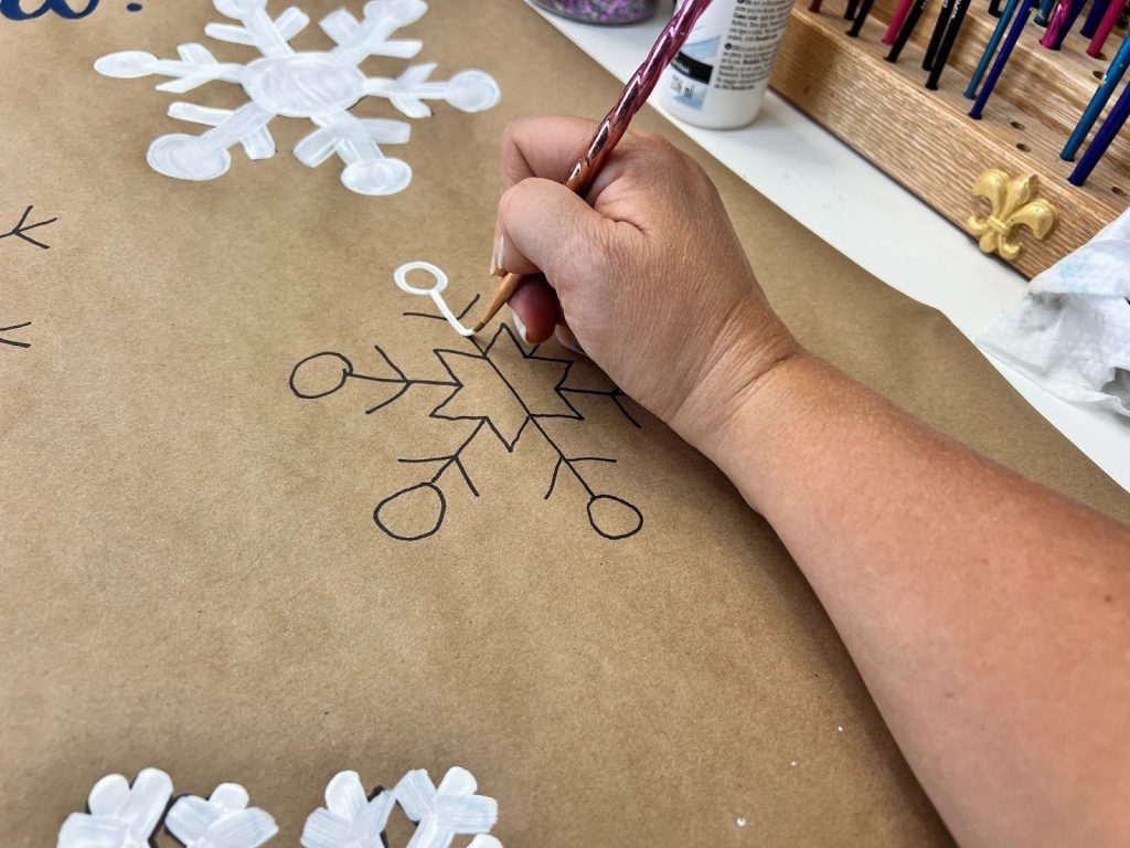 someone's hand drawing a snowflake