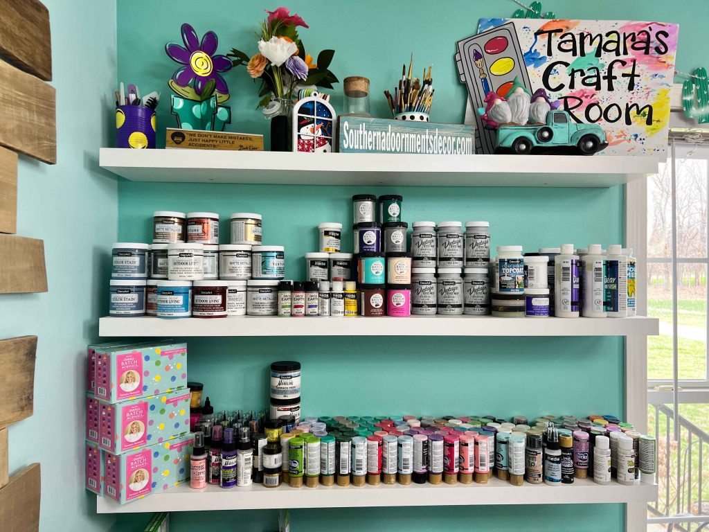 craft room shelves with colorful decor and paint bottles on them