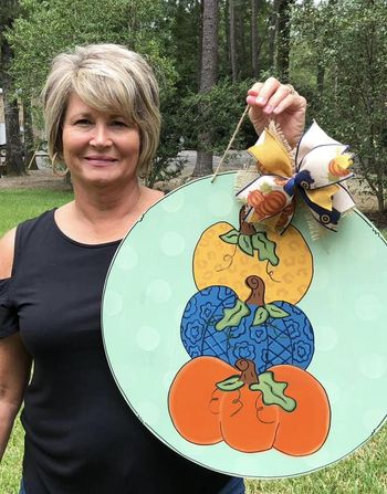 Cindy fowler, a pc member, holding up her pumpkin door hanger design