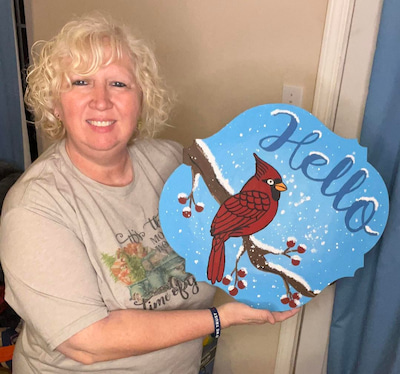 sandy mcquarter, a pc member, holding up her cardinal door hanger project